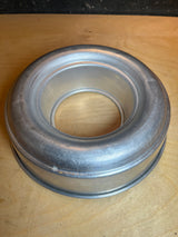 Circular Bundt pan - vintage aluminum, donut-shaped with straight sides, ideal for ring cakes or jello. Visible small dings indicate its aged charm.