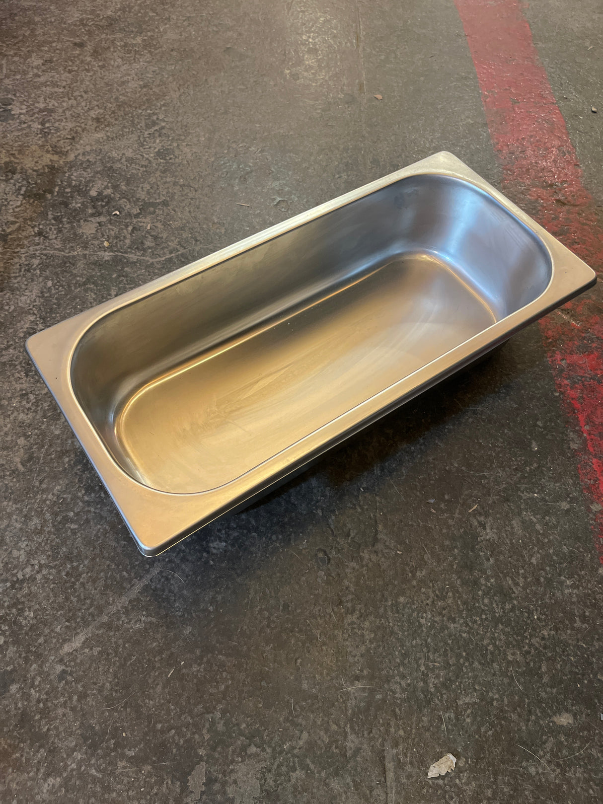 Set of 3 stainless steel steam pans with serving ring, empty on textured floor, ideal for kitchen prep and organizing food at events.