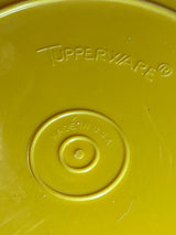 Underside of Tupperware golden yellow pitcher's lid displaying embossed “TUPPERWARE®” logo and “MADE IN U.S.A.” stamp.