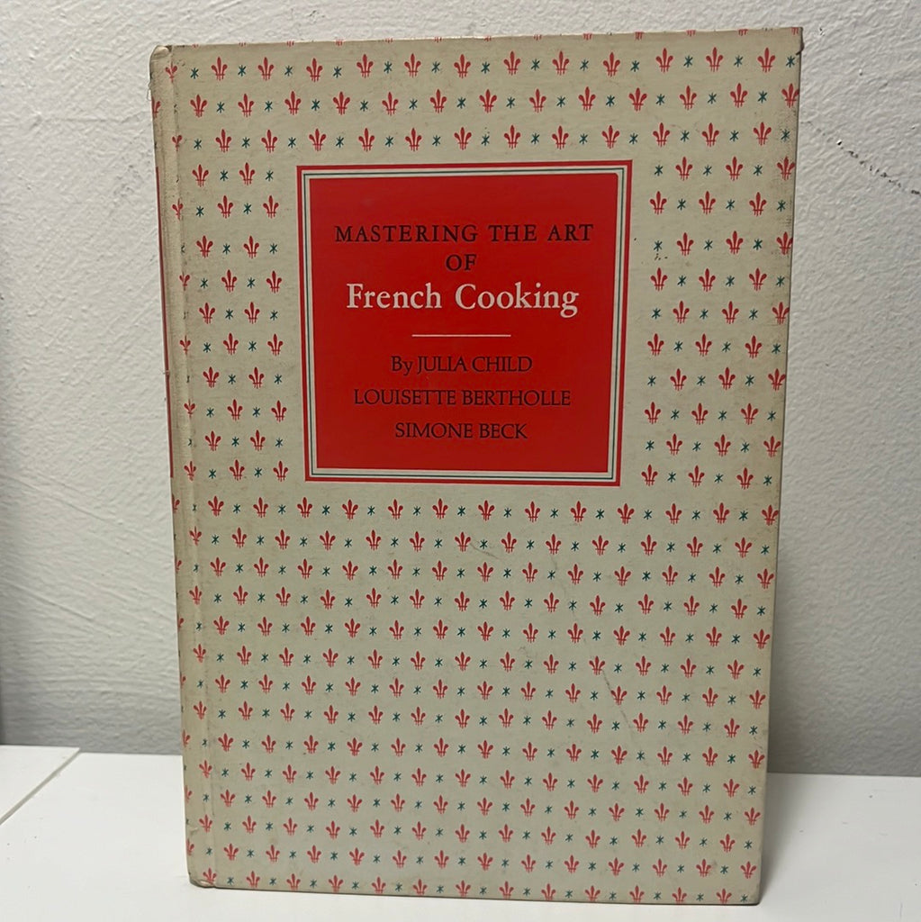 Julia Child Mastering the Art of French Cooking book cover with intricate pattern featuring a Fleur-de-lis. From Spoons Kitchen Exchange. 