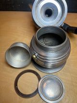 Disassembled RARE Alessi Pulcina 6-cup moka pot, showcasing components: bottom water chamber, upper collection chamber, coffee filter basket, perforated filter plate, and rubber gasket.