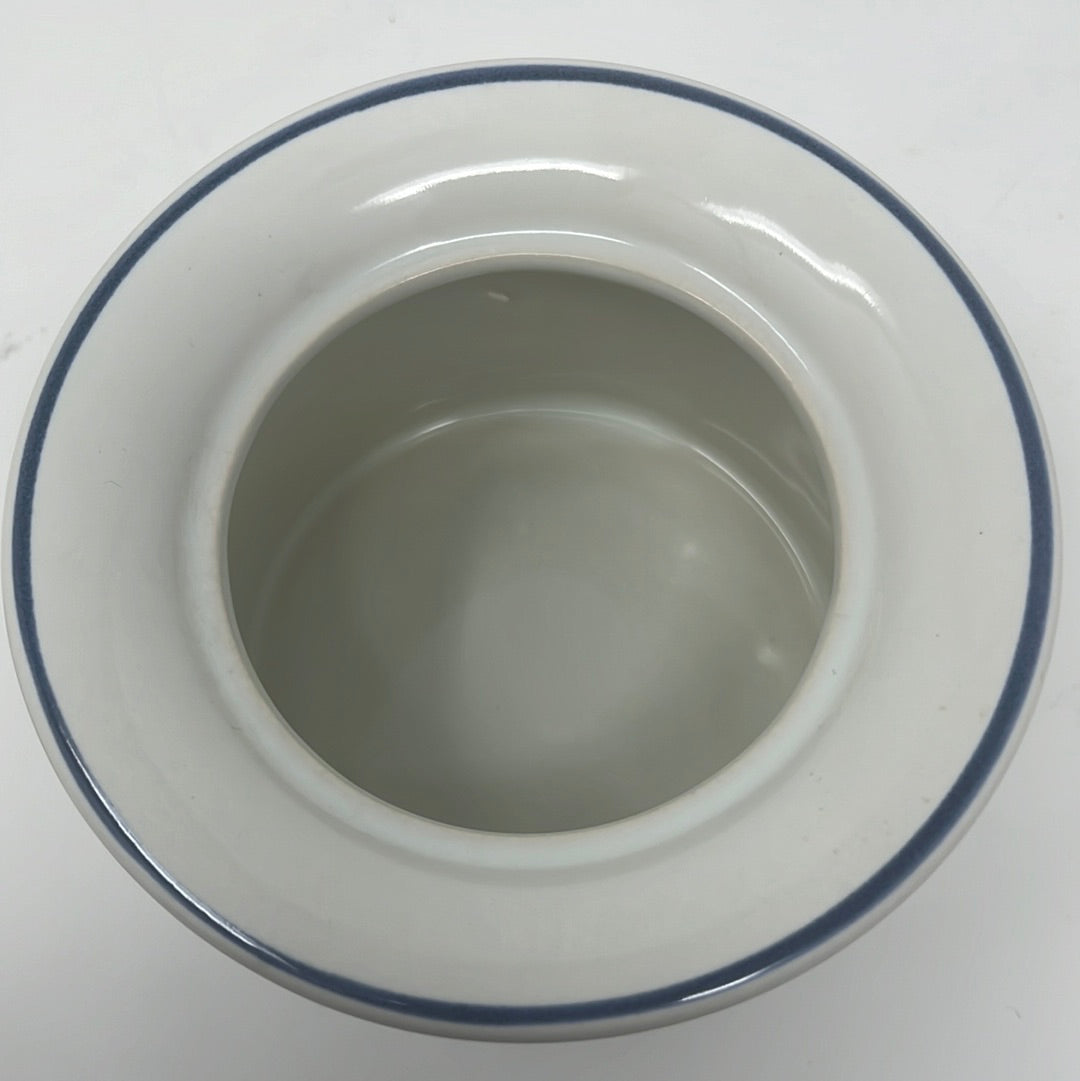 Studio Nova ceramic dish with lid, a white bowl with blue rim, close-up view.