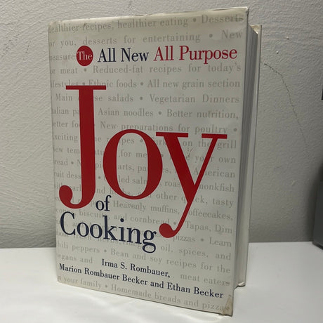 The New All Purpose Joy of Cooking book on a table, emphasizing its role as a trusted, comprehensive cookbook for modern American cooking and baking.