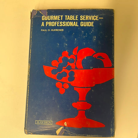 Gourmet Table Service - A Professional Guide book displayed with a bowl of fruit, emphasizing fine dining skills for waitstaff through detailed instructions and illustrations.