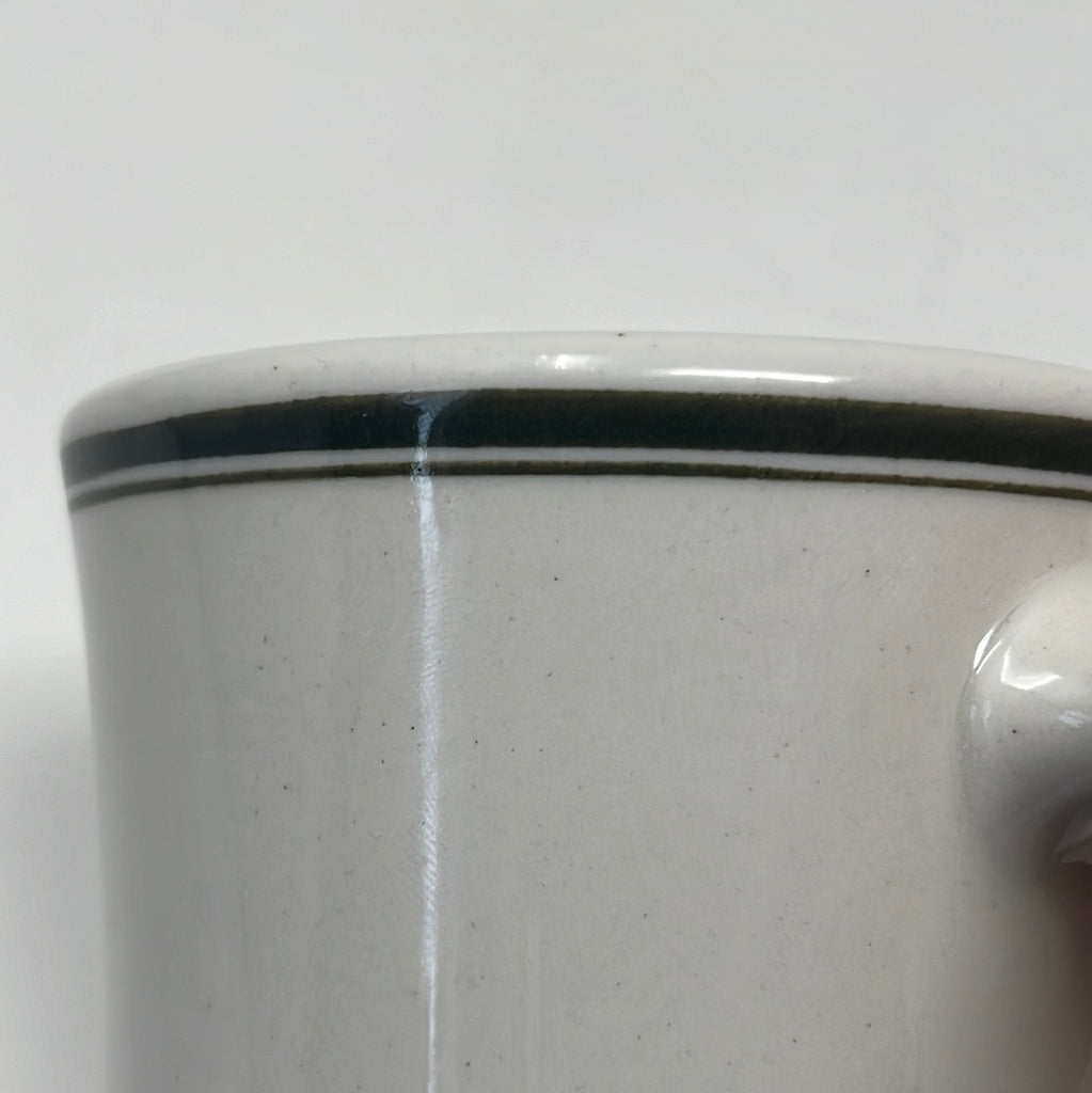 Close-up of Victor coffee mugs in white ironware with olive green rim accents, designed for military and everyday use.
