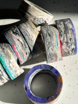 Napkin rings from Reimagined Recycling: Chunky, cylindrical rings with marbled striations, showcasing a unique, lightweight design, crafted from multi-layered recycled materials. Each set is distinct.