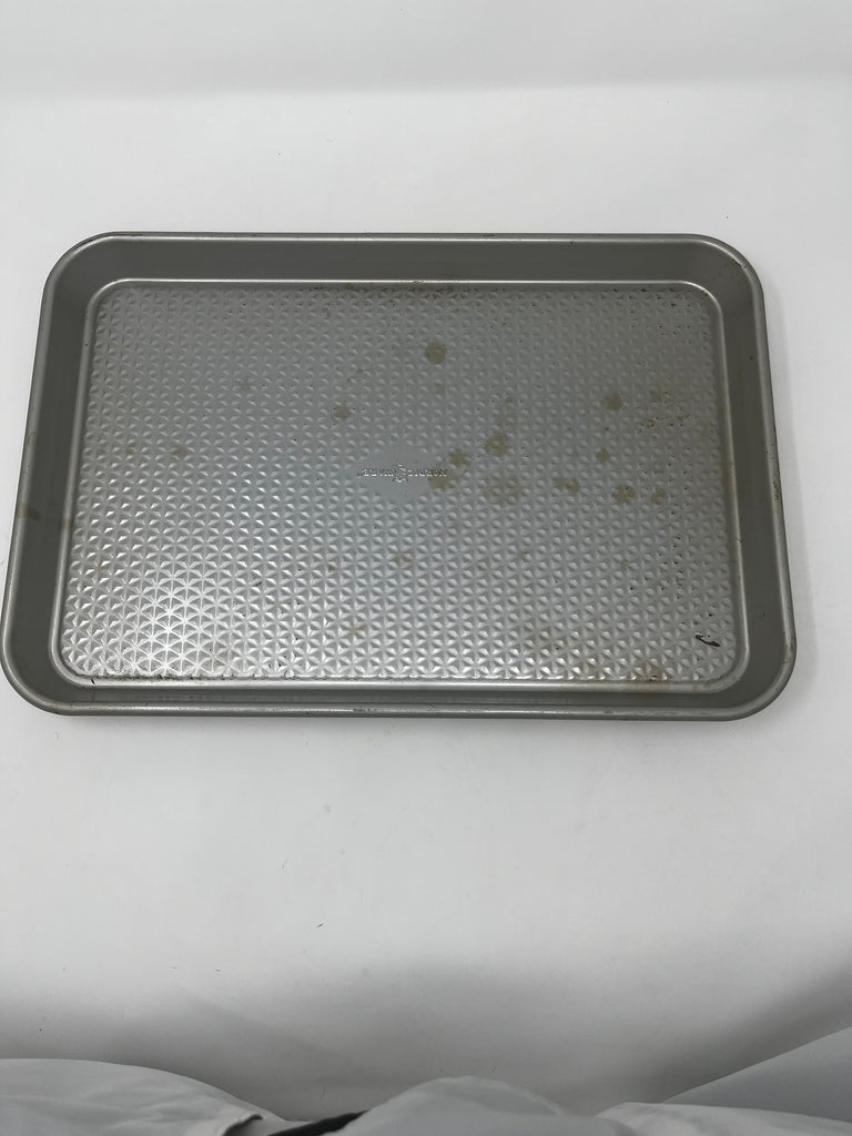 Gray Nordicware baking pan with some light brown spots. Set on a white background.