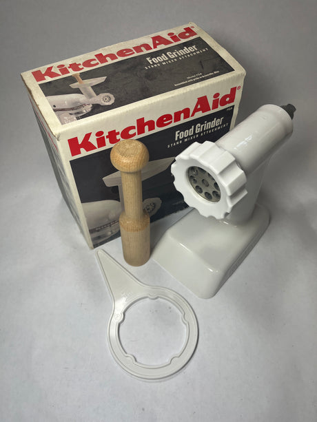 KitchenAid mixer food grinder attachment next to a worn box with all original parts in excellent condition.